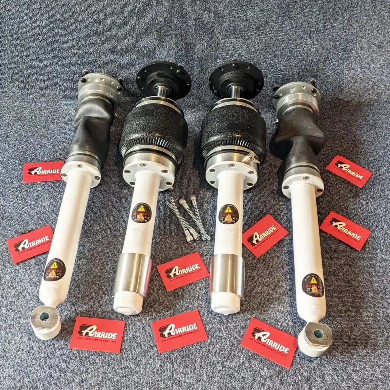 BMW E60 air suspension kit showing white shocks with black airbags on blue background