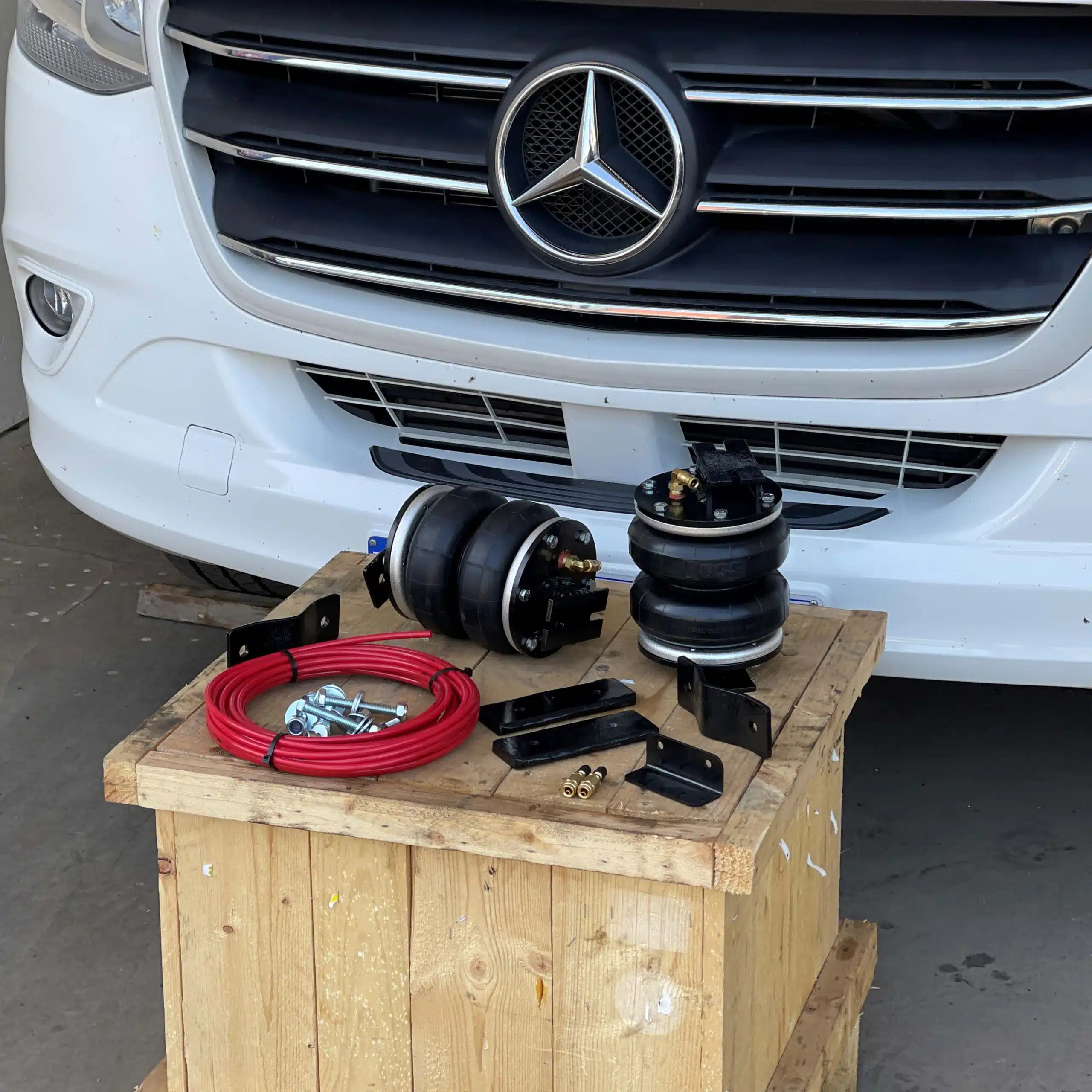 Sprinter/Crafter load support kit laid out on a wooden table in front of a Mercedes Sprinter van