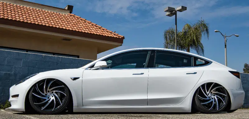 Side shot of white tesla model three with air suspension fully lowered