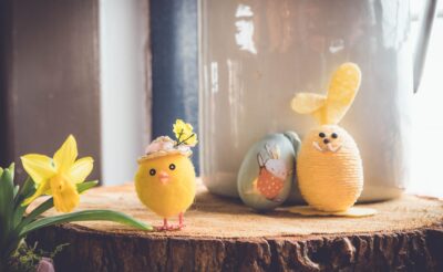 Easter eggs, chickens and flowers on a wooden background