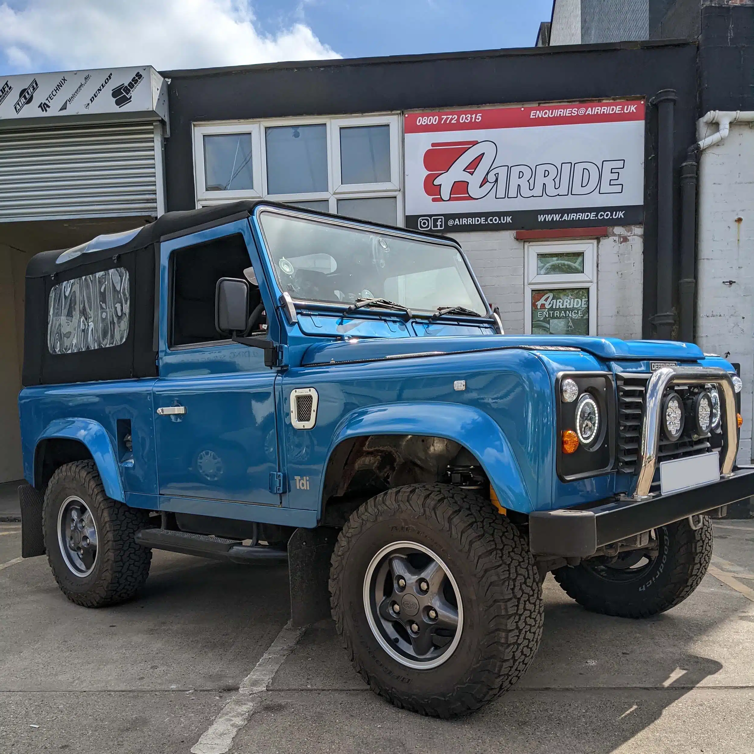 Lifted 1997 Defender parked sideways outside AirRide workshop