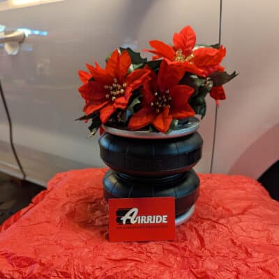 Decorated air spring with AirRide business card in front of a custom air suspension build Decorated air spring with AirRide business card in front of a custom air suspension build