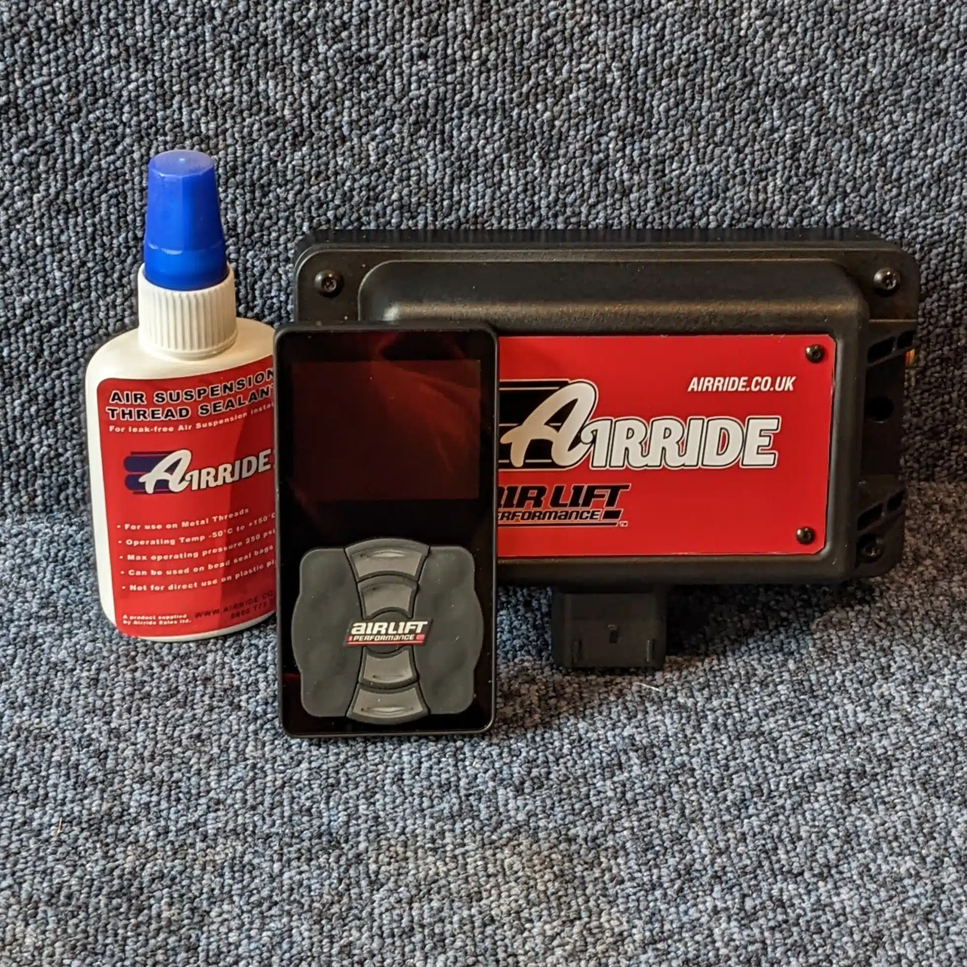 AirLift Performance 3P remote and manifold with AirRide thread sealant on blue background